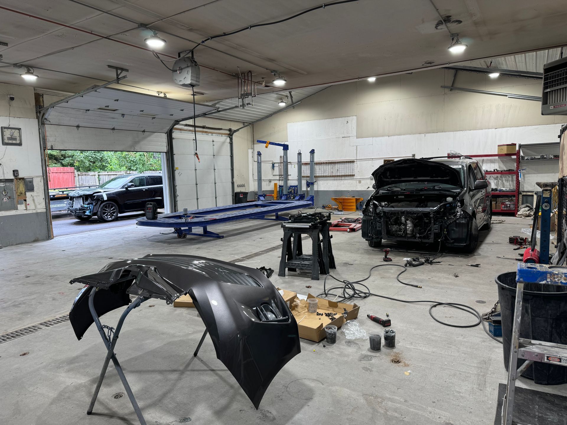 A man is looking at a damaged car with a clipboard.