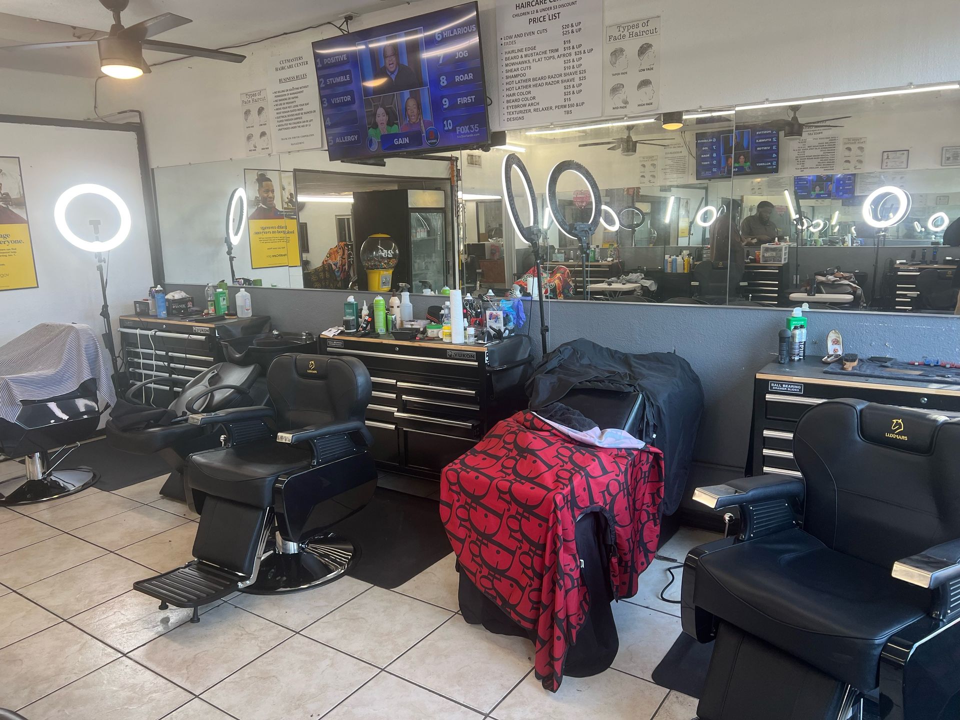 A barber shop with a lot of chairs and a television on the wall.