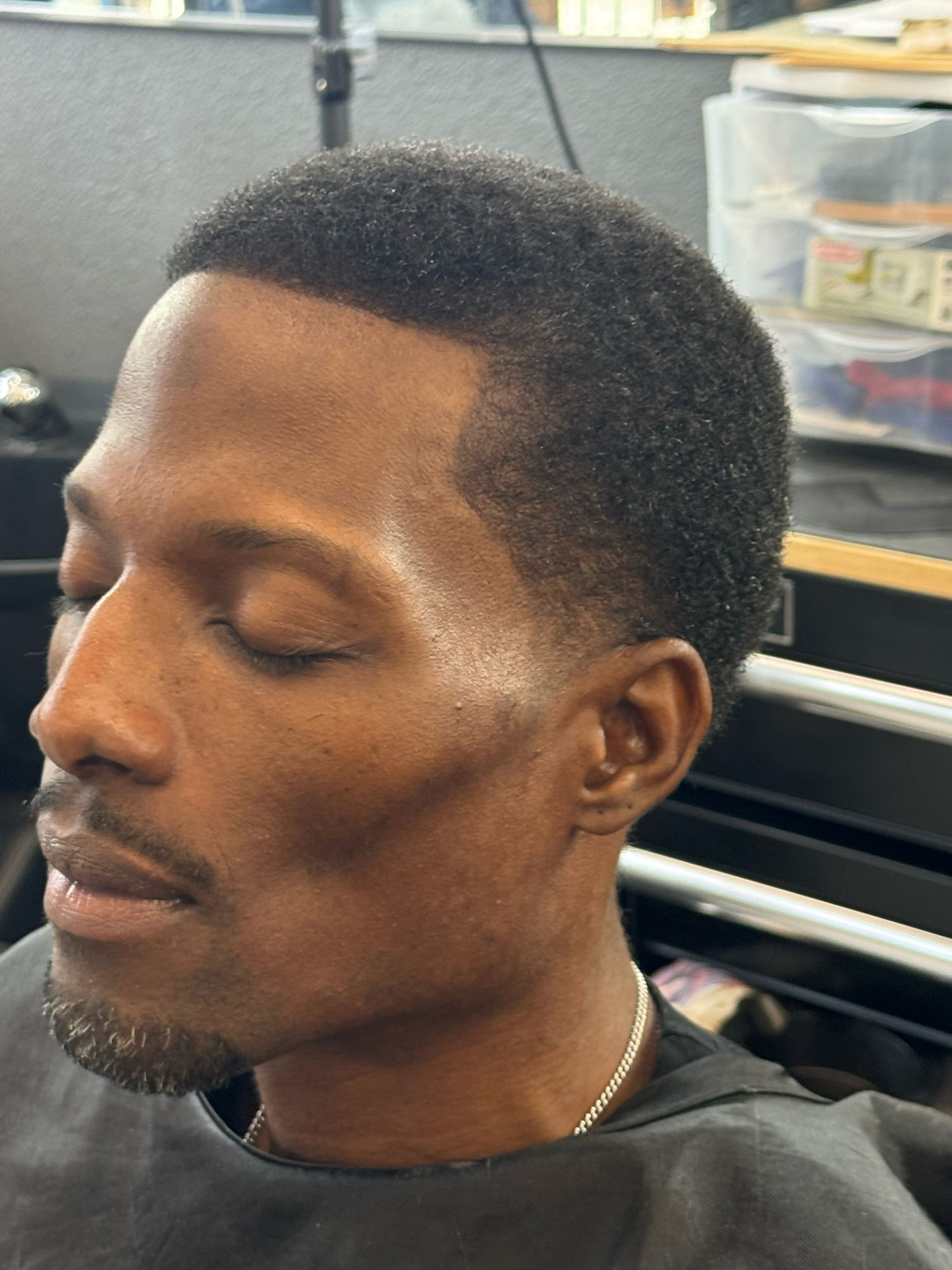 A man is getting his hair cut at a barber shop.