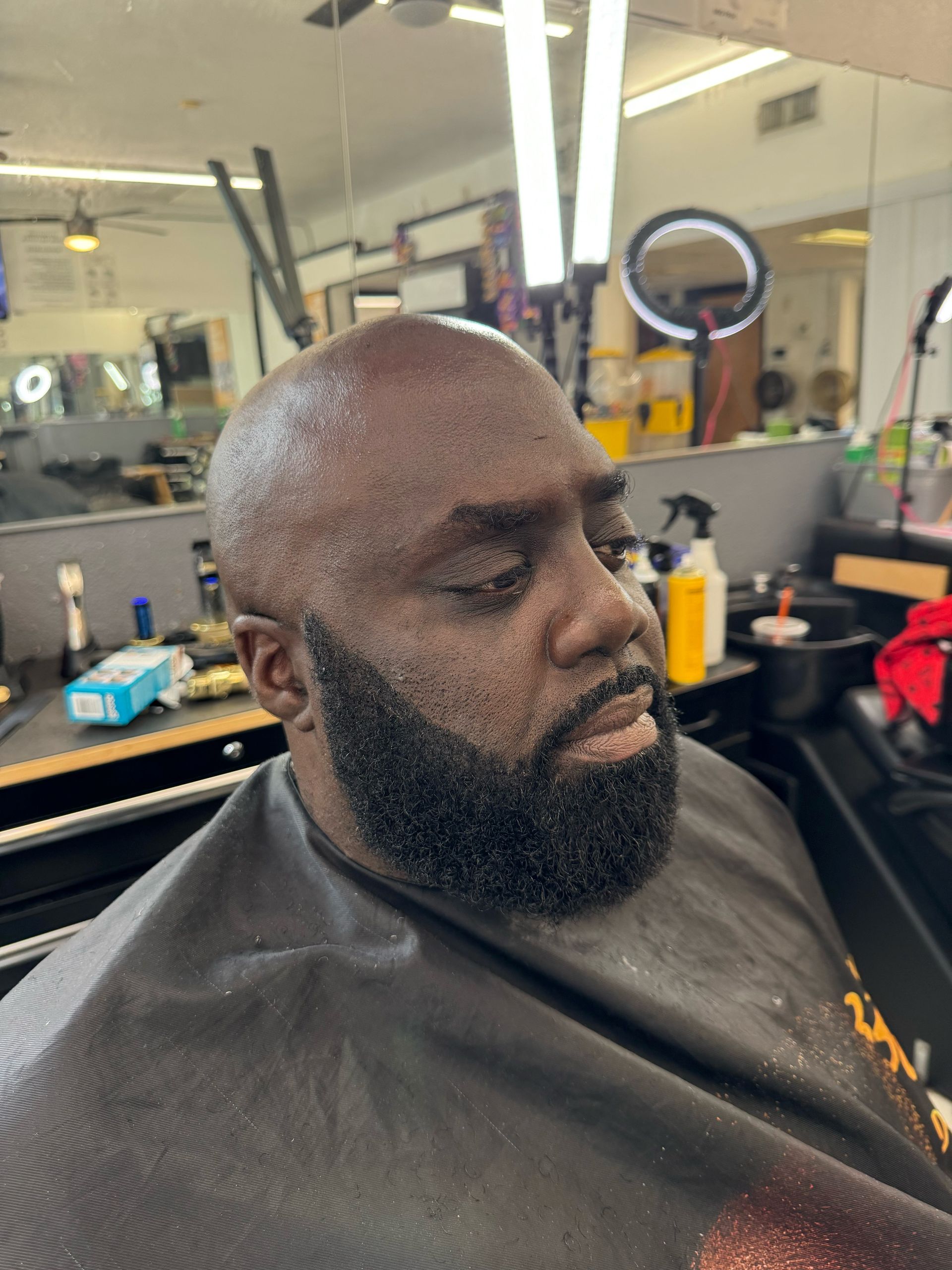 A man with a beard is getting his hair cut at a barber shop.