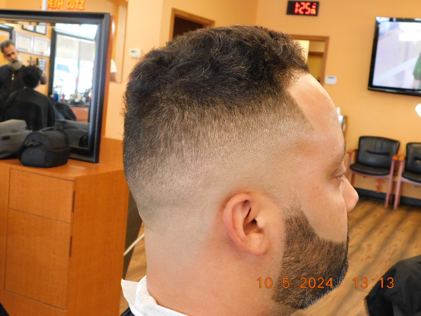 A man with a beard is getting his hair cut at a barber shop.