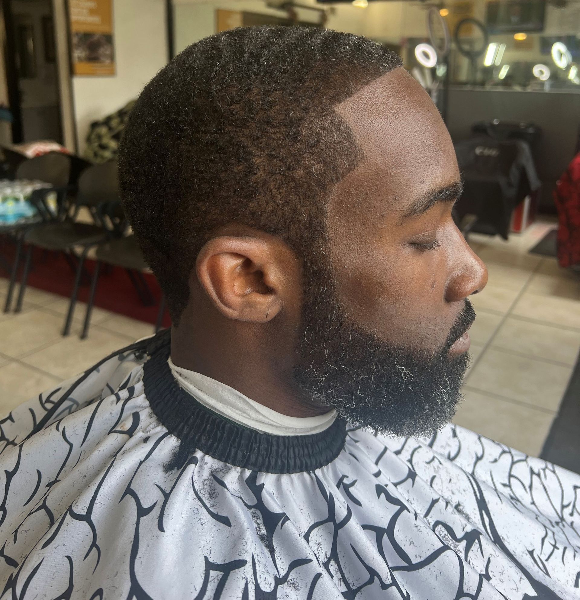A man with a beard is getting his hair cut at a barber shop