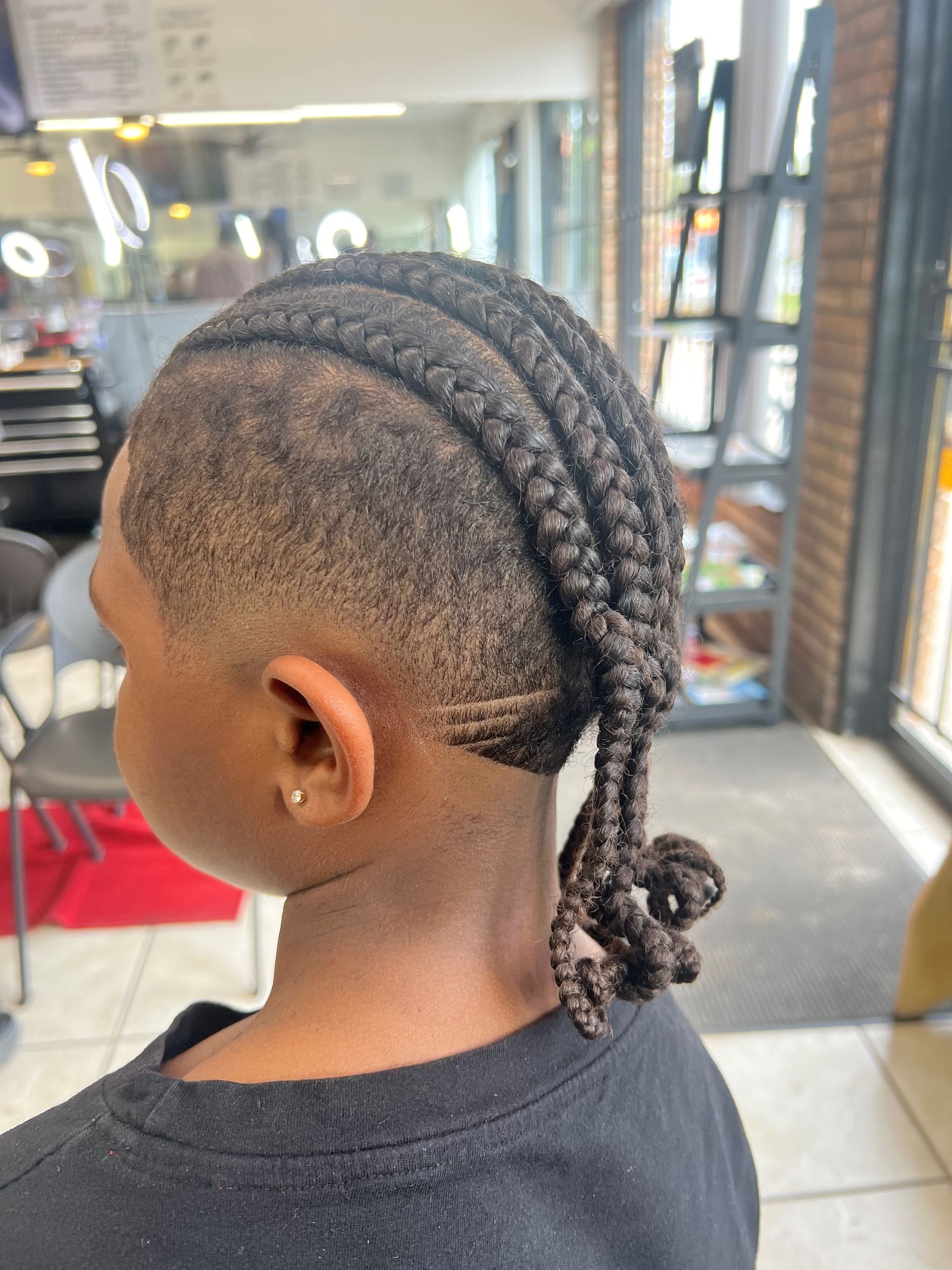 A close up of a person 's head with braids and a shaved head.