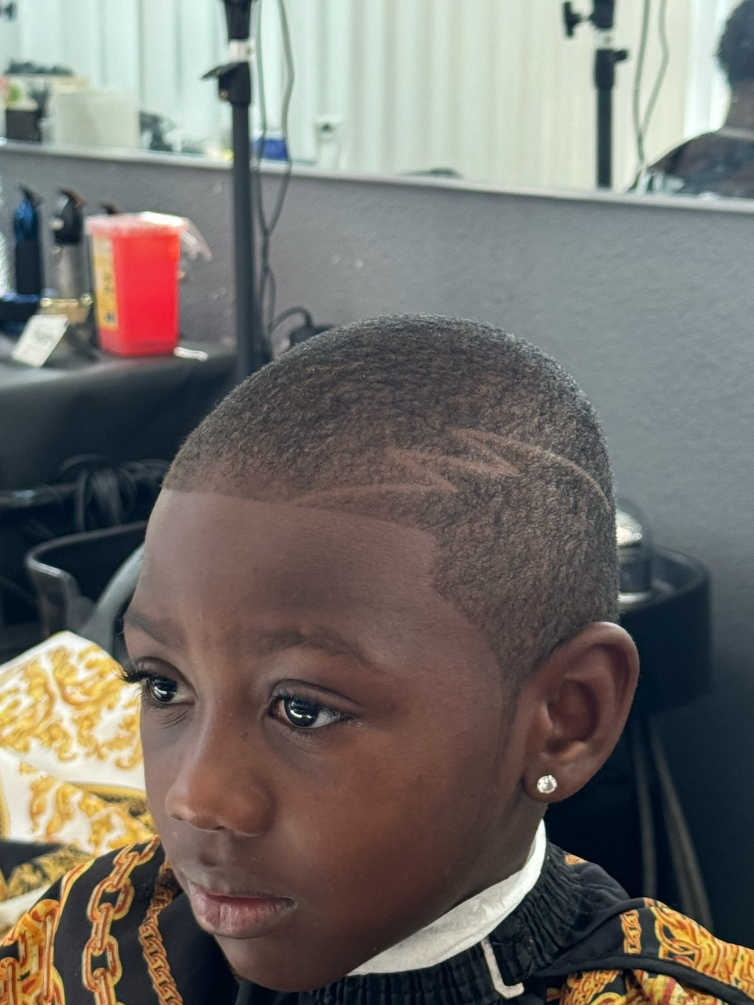A young boy is getting his hair cut at a barber shop.