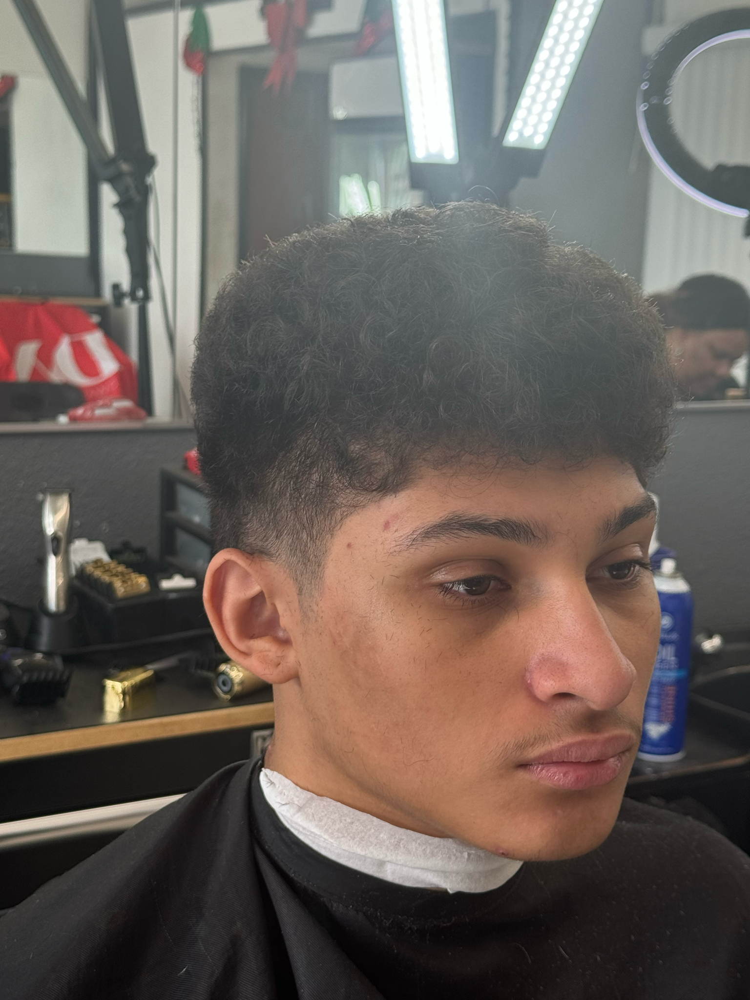 A young man is getting his hair cut at a barber shop.