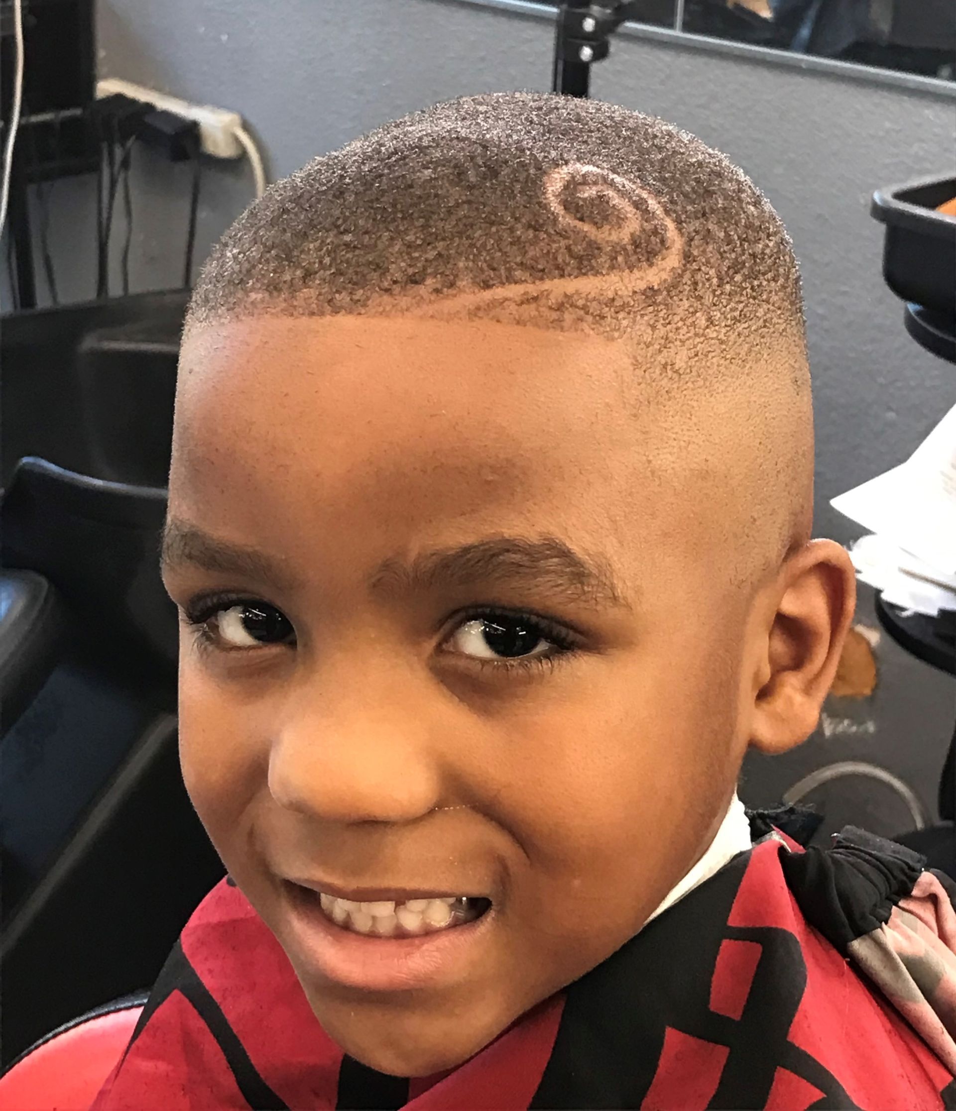 A young boy is getting his hair cut at a barber shop.