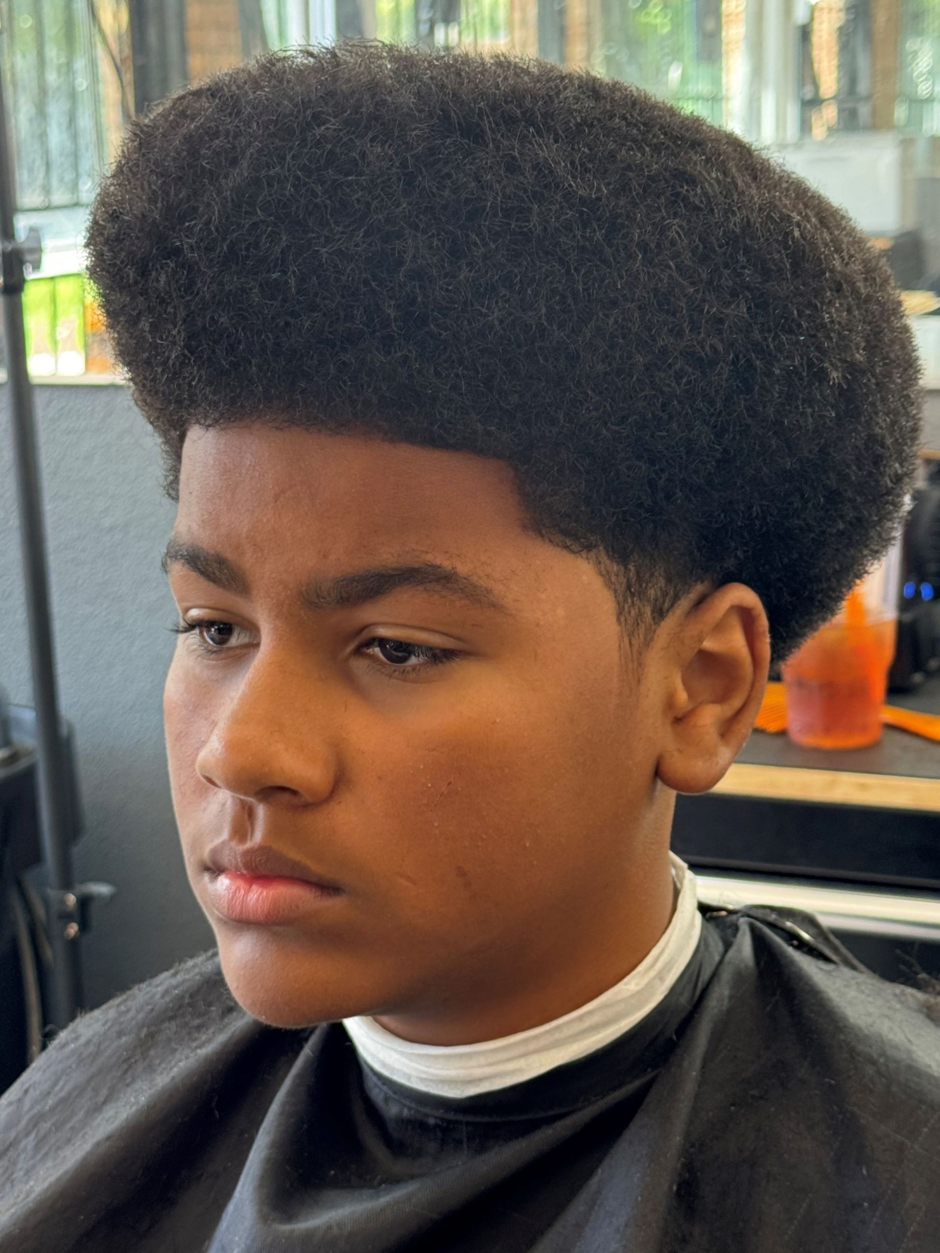 A young boy is getting his hair cut at a barber shop.