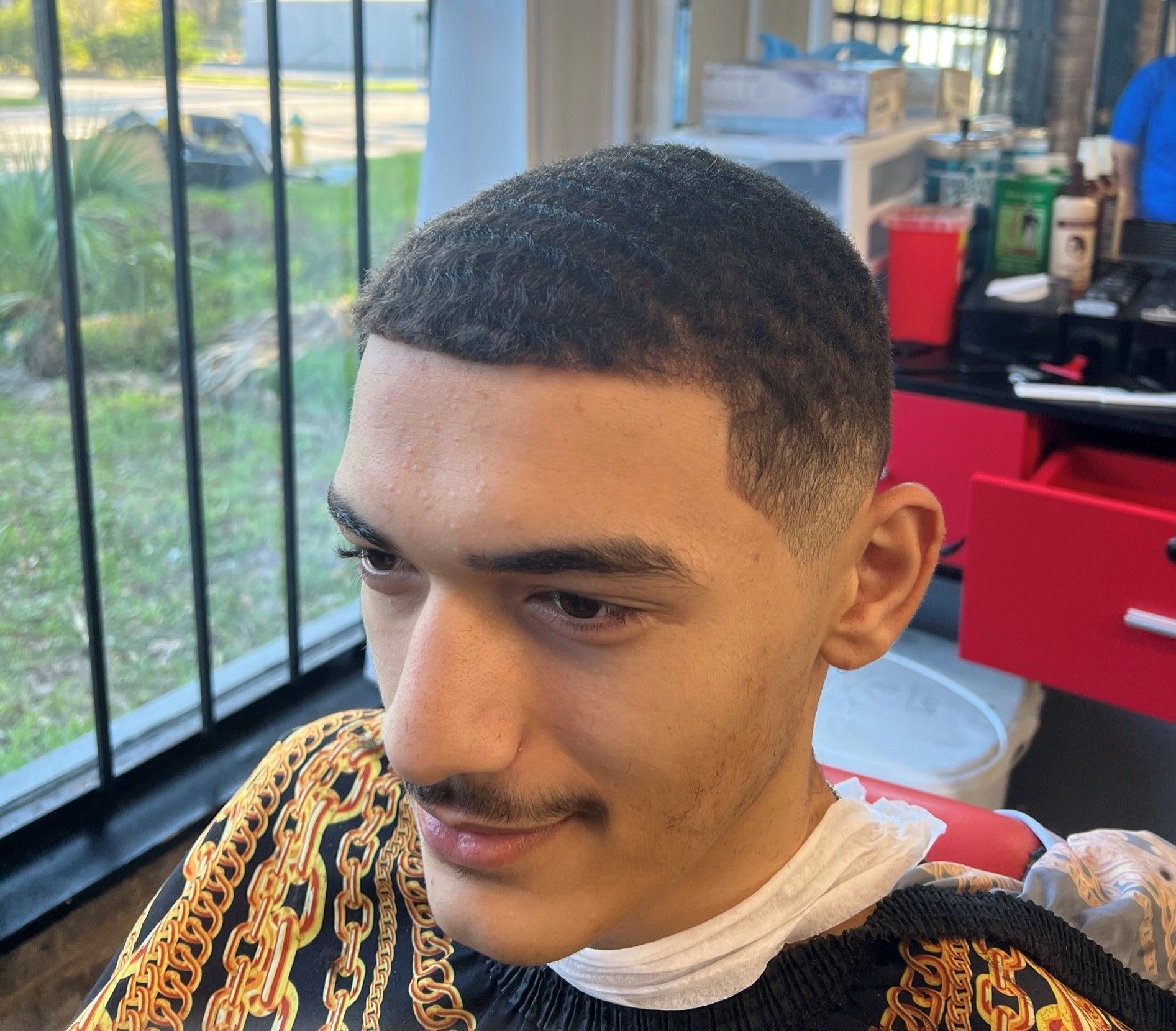 A man with a mustache is getting his hair cut at a barber shop.
