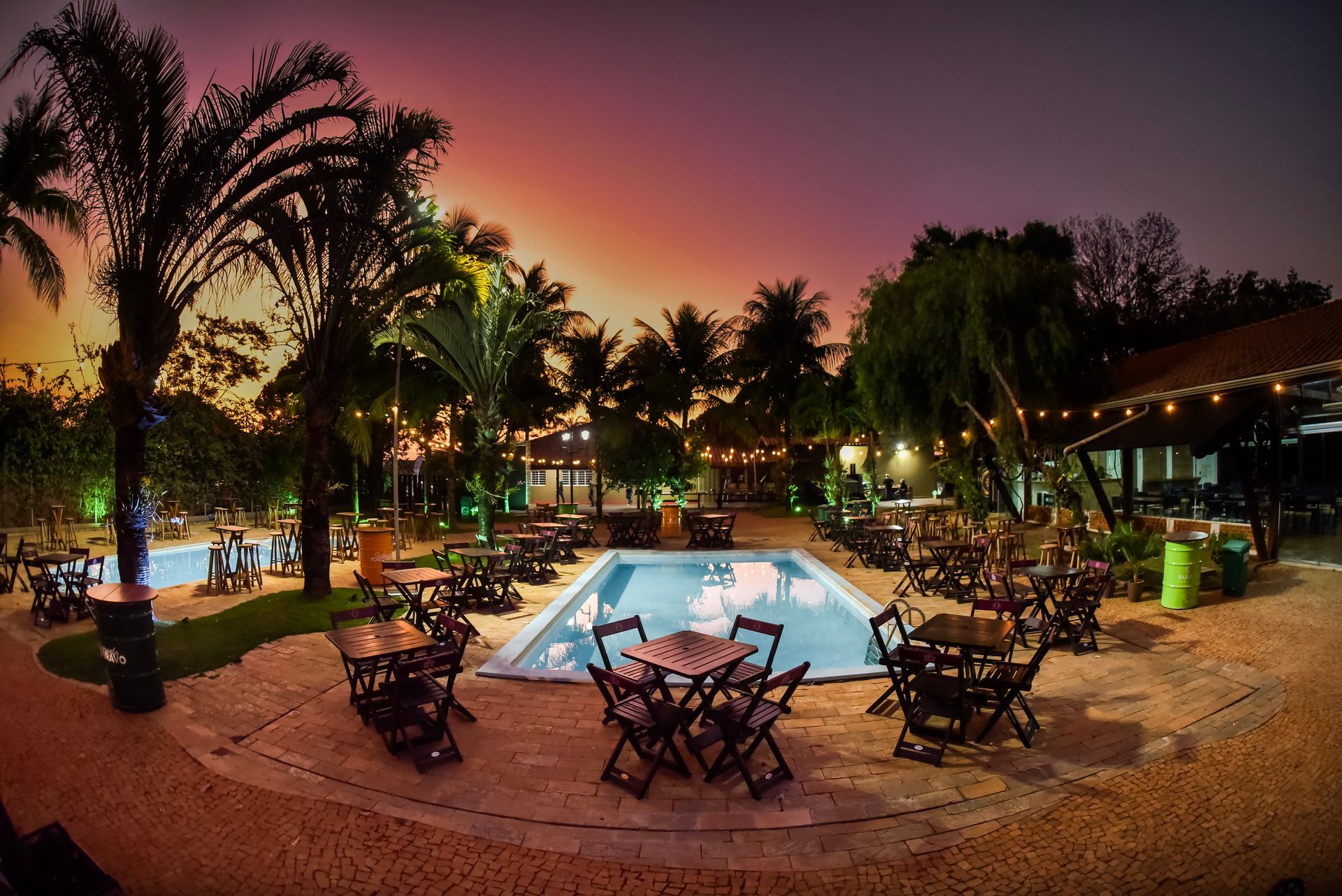 Grande evento com banda no palco, flores brancas e pessoas em uma sala bem iluminada.