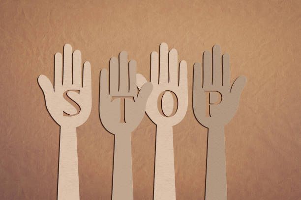 A woman in a hoodie is covering her face with her hand.