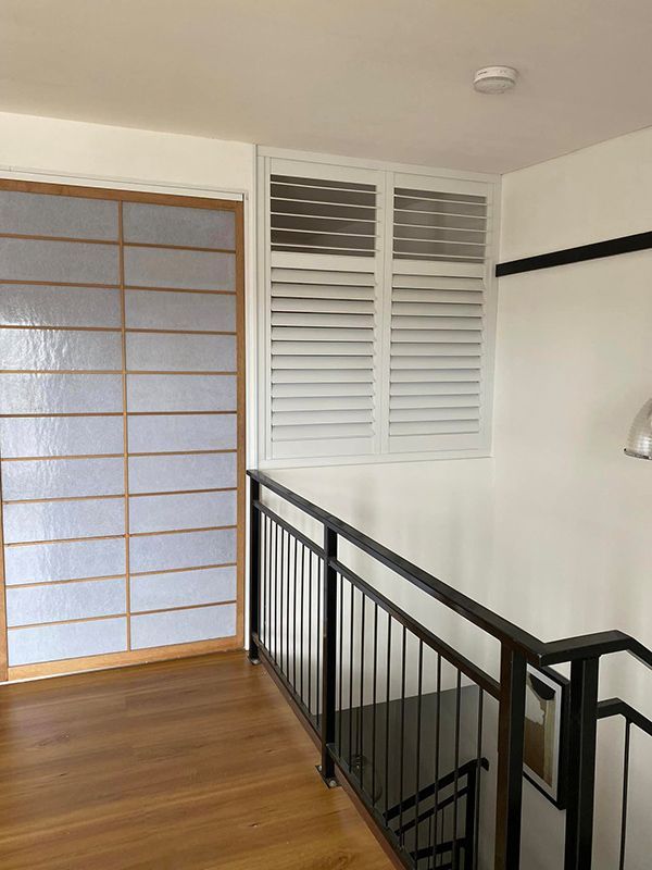 A Staircase With A Black Railing And White Shutters — Window Coverings in Gold Coast, QLD