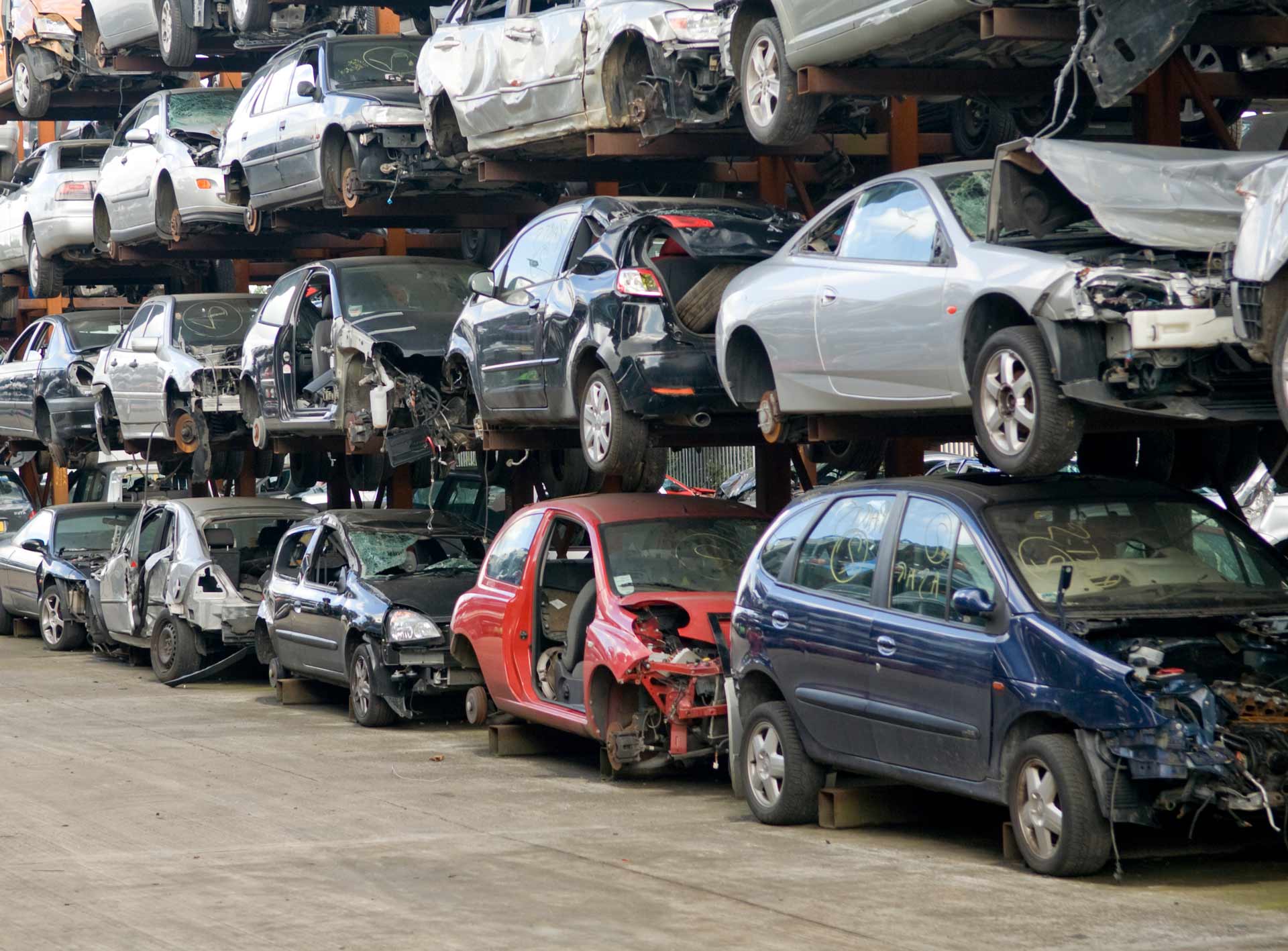 Rows of damaged cars stacked on metal racks with missing doors, wheels, and parts. Rows of damaged cars stacked on metal racks with missing doors, wheels, and parts.
