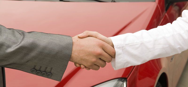 handshake in front of red car