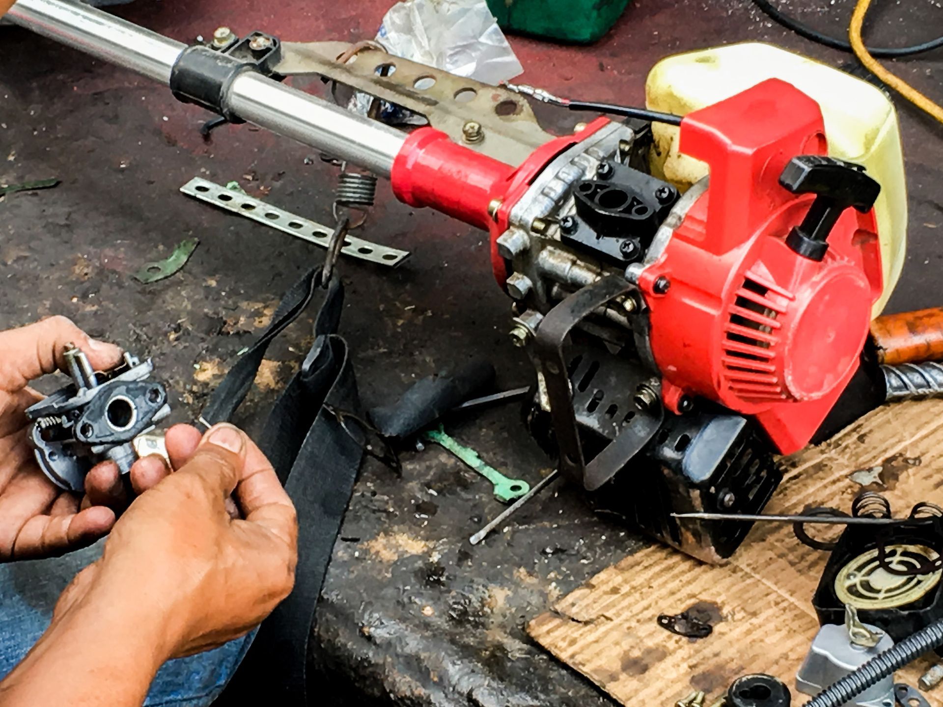 A man is repairing a lawn mower on a table.