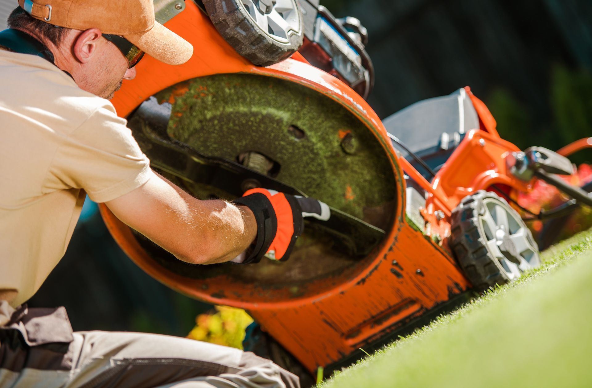 A man is cutting grass with an orange lawn mower.
