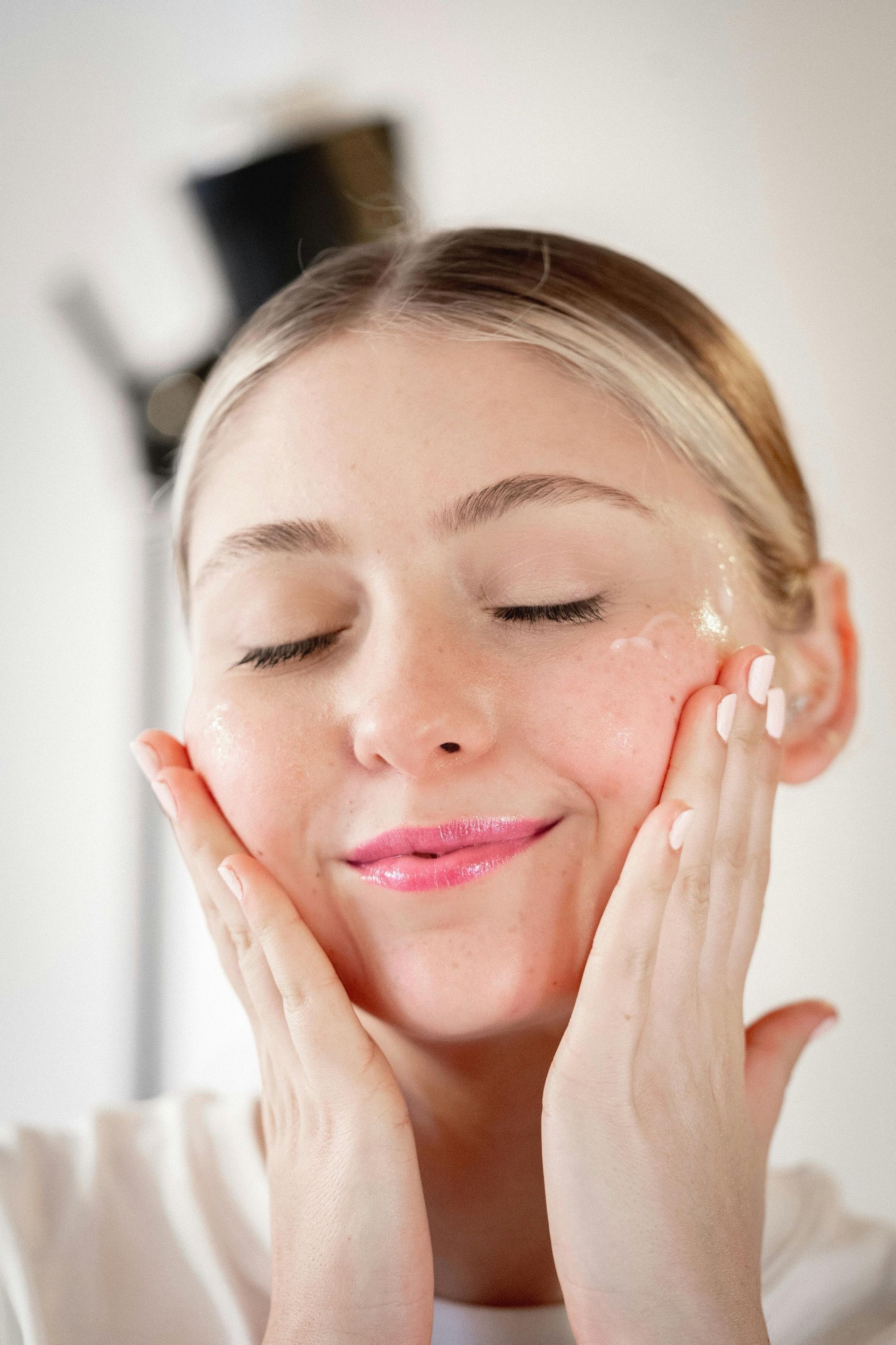 A patient admiring how health skin after a Glo2 Facial at The Luxe Dose in Belmont, MA.