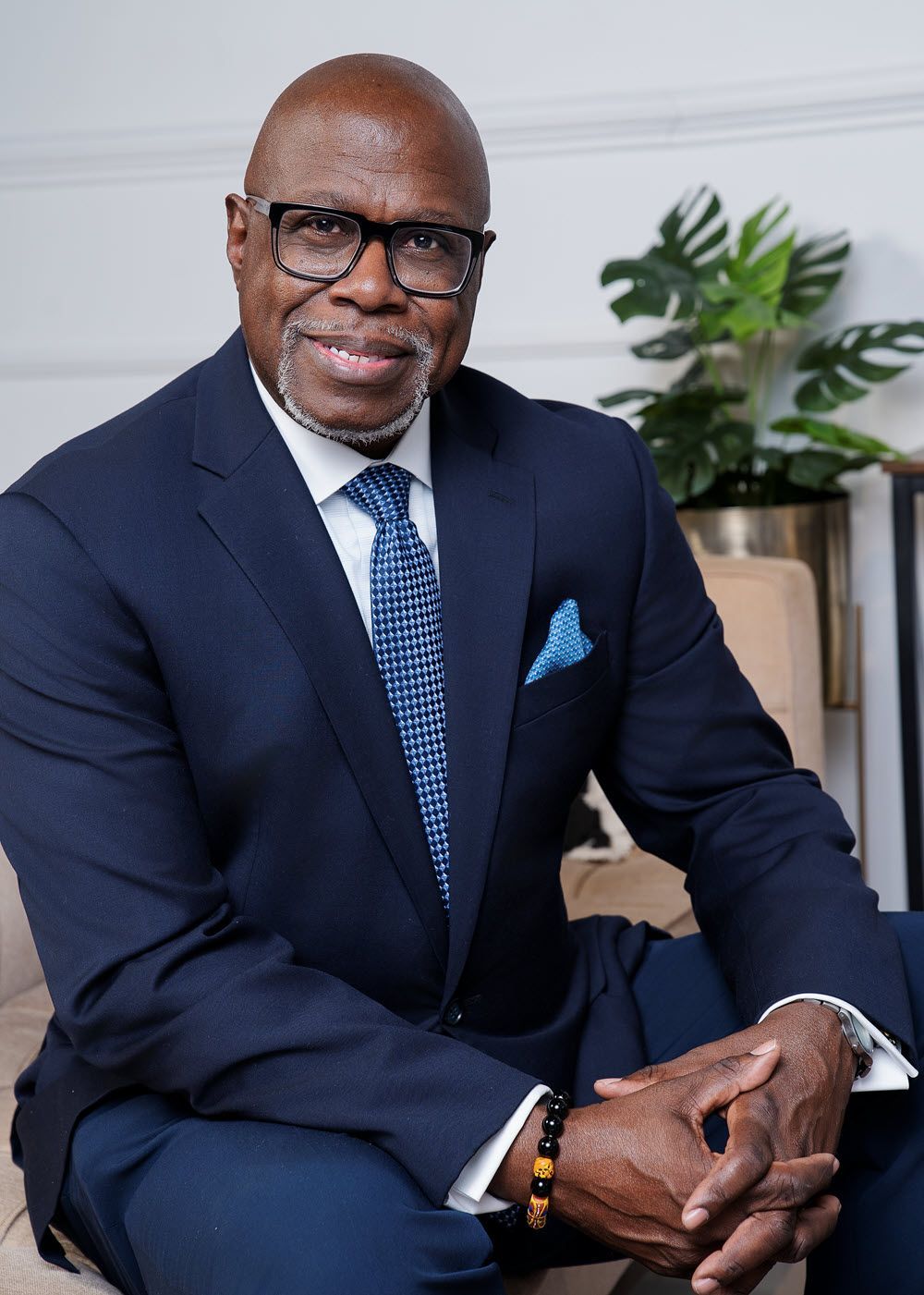 Beach scene: straw umbrella shades a blue folding chair; turquoise water and sky.