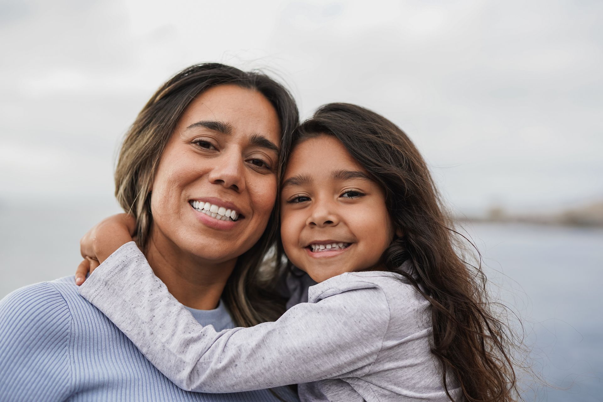 Woman and child smiling and embracing outdoors.