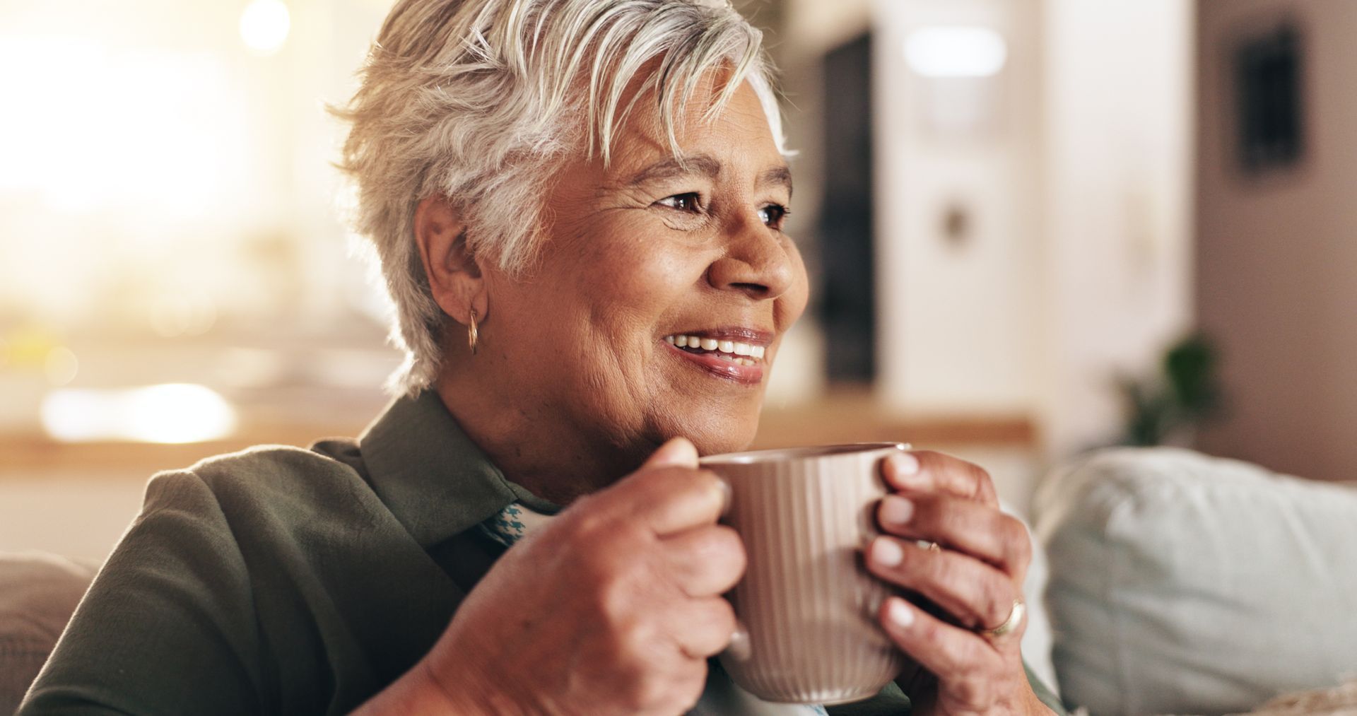 Smiling person holding a mug, indoors, natural light.