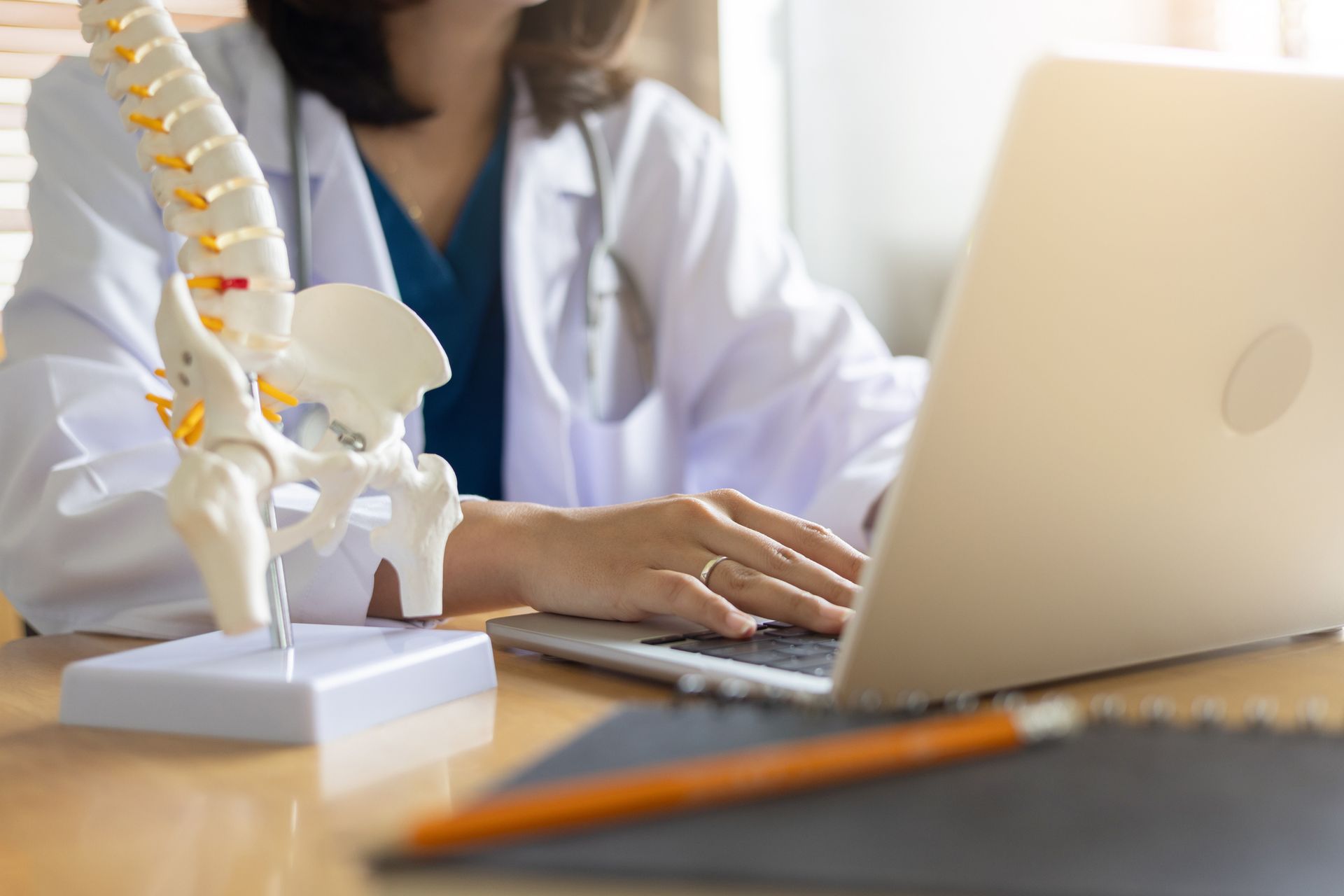 A doctor is sitting at a desk using a laptop computer.