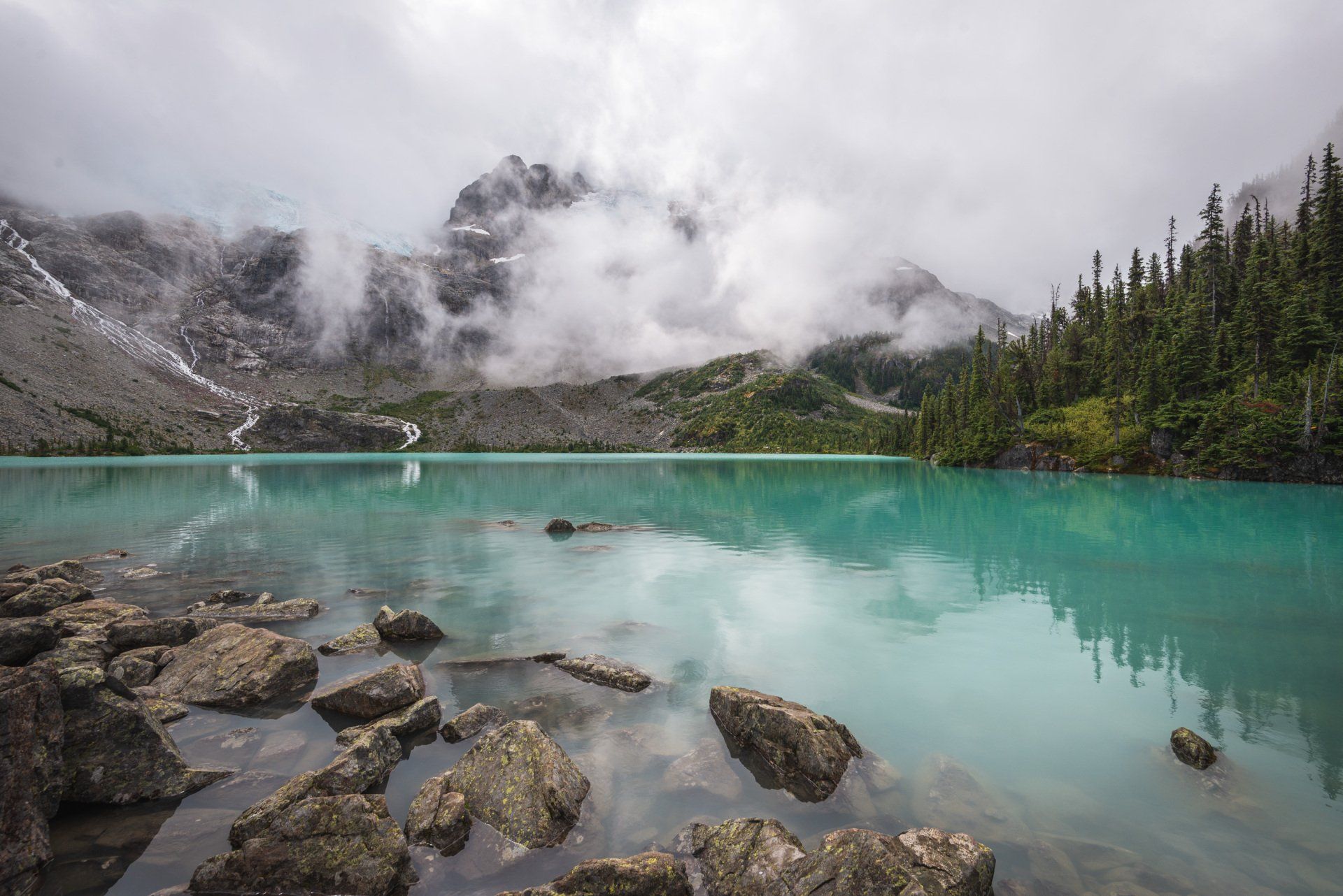 Upper Joffre lake with surrounding mountains and glacier behind the low clouds, Joffre Lakes Provincial Park, BC, Canada