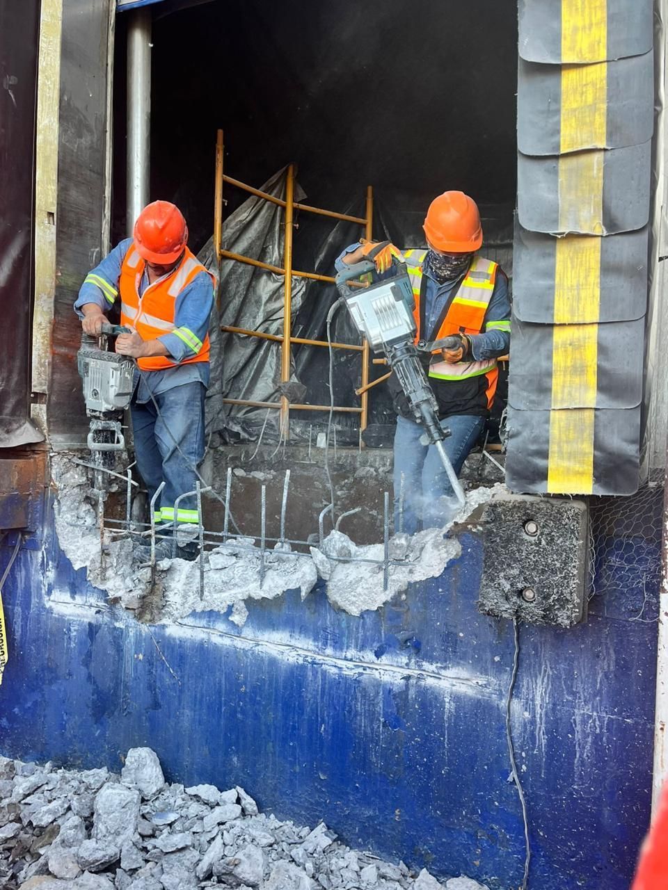 Dos obreros de la construcción utilizan martillos neumáticos para demoler una estructura de hormigón.