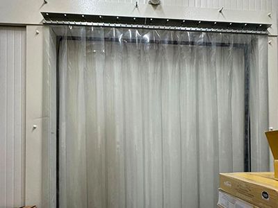 Puerta con tiras de plástico transparente en una habitación blanca.