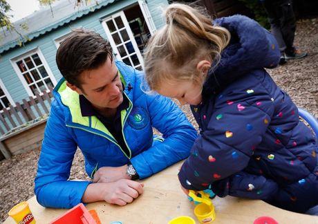A man and a little girl are playing with play dough at a table.