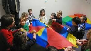 A group of children are playing with a colorful parachute.