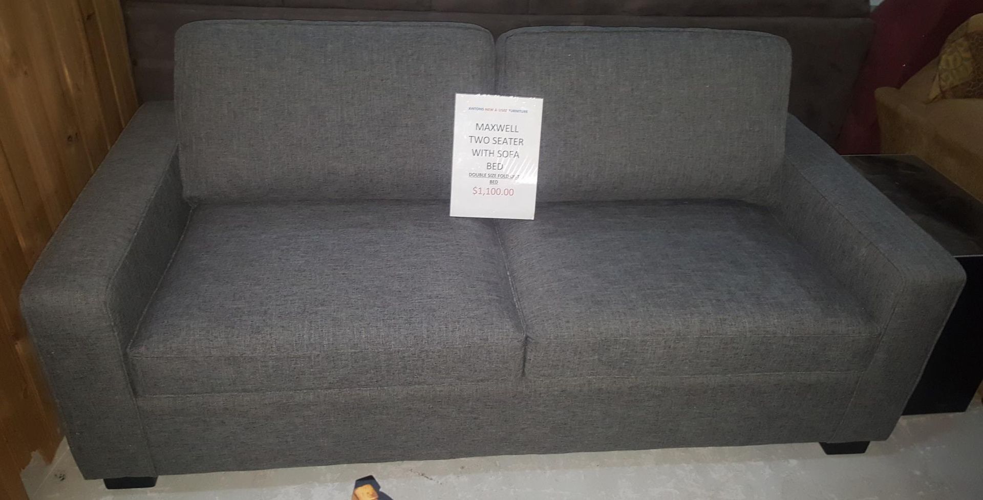 A Grey Couch With a Price Tag on It is Sitting on a White Floor — Anton's New & Used Furniture In Ciccone, NT