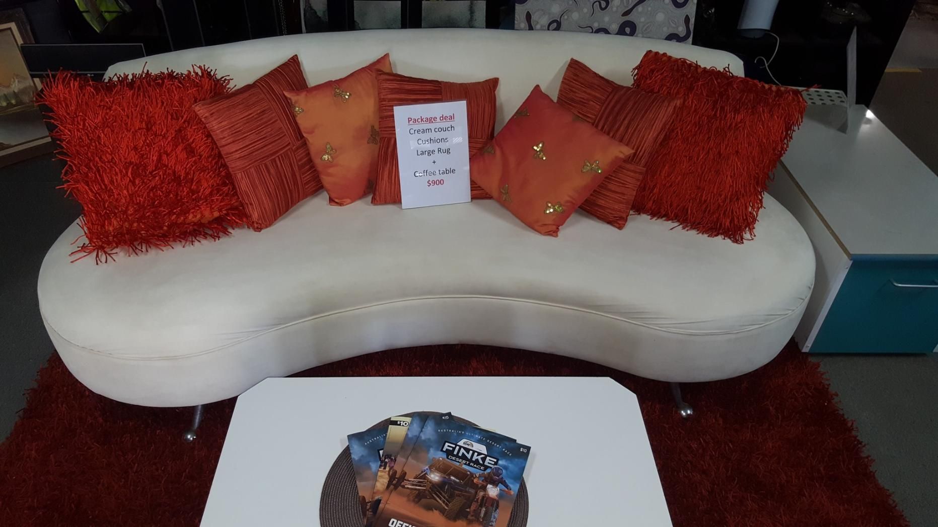 A White Couch With Red Pillows Sits Next to a Coffee Table — Anton's New & Used Furniture In Ciccone, NT