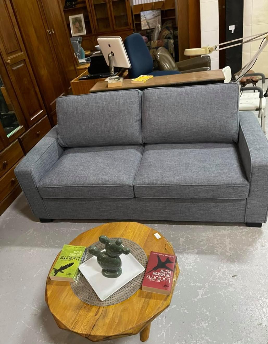 A Grey Couch Is Sitting Next To A Wooden Coffee Table In A Living Room — Anton's New & Used Furniture In Ciccone, NT