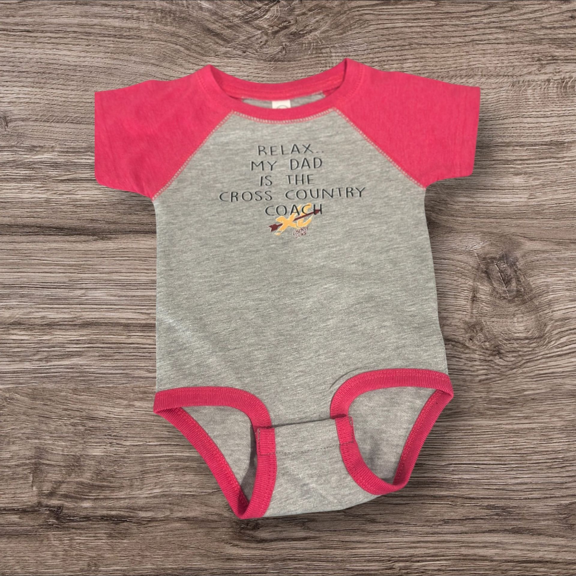 Gray and pink baby onesie with text: "Relax, My Dad is the Cross Country Coach."