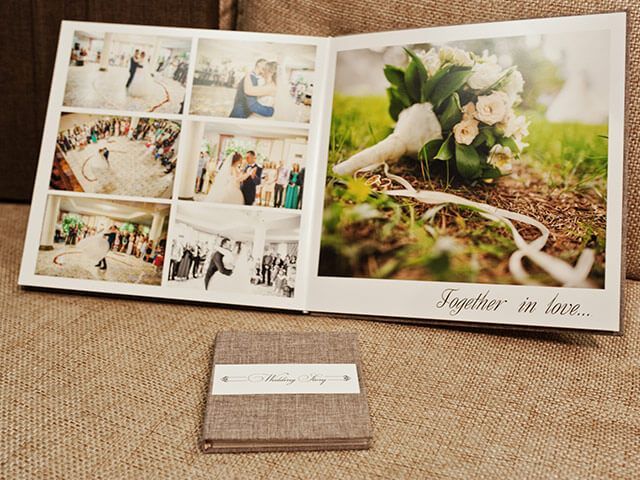 A wedding album is sitting on a couch next to a wallet.