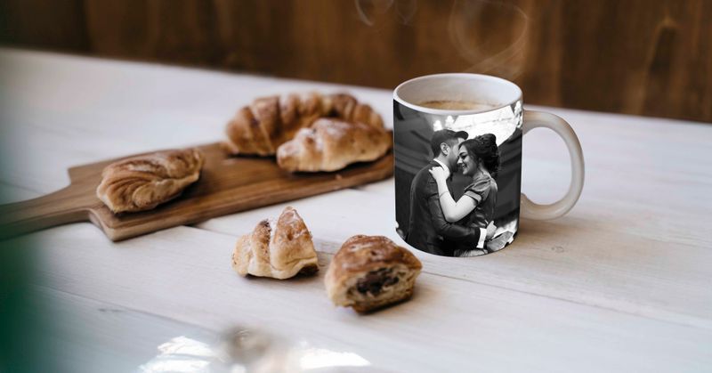 A coffee mug is sitting on a table next to croissants.