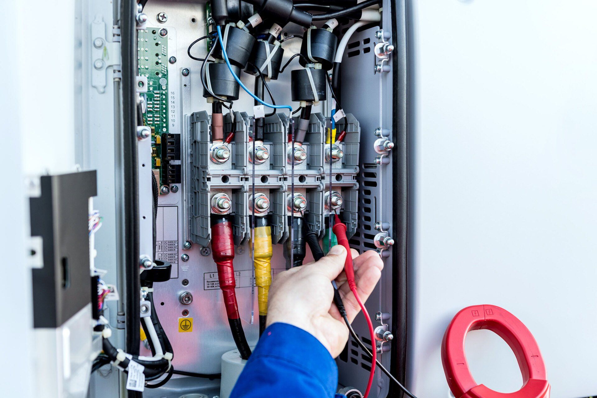 Eine Person arbeitet mit einem Multimeter an einem Schaltkasten.
