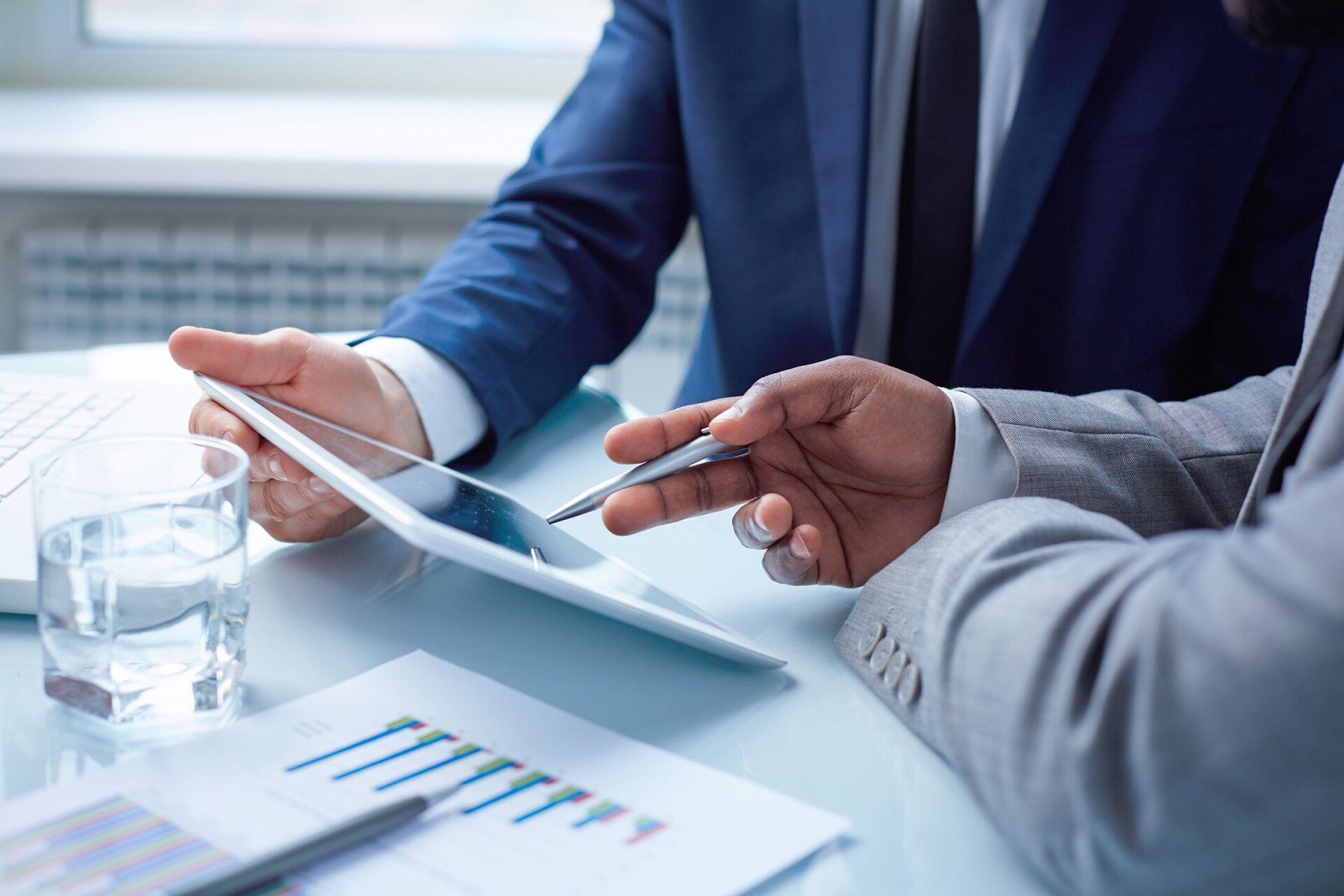 Zwei Geschäftsleute sitzen an einem Tisch und schauen auf ein Tablet.