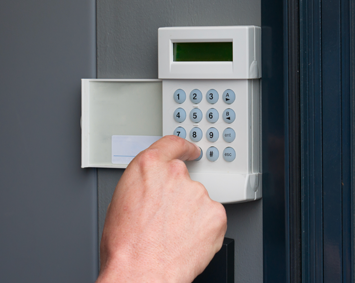 A person is pressing a keypad on a door.