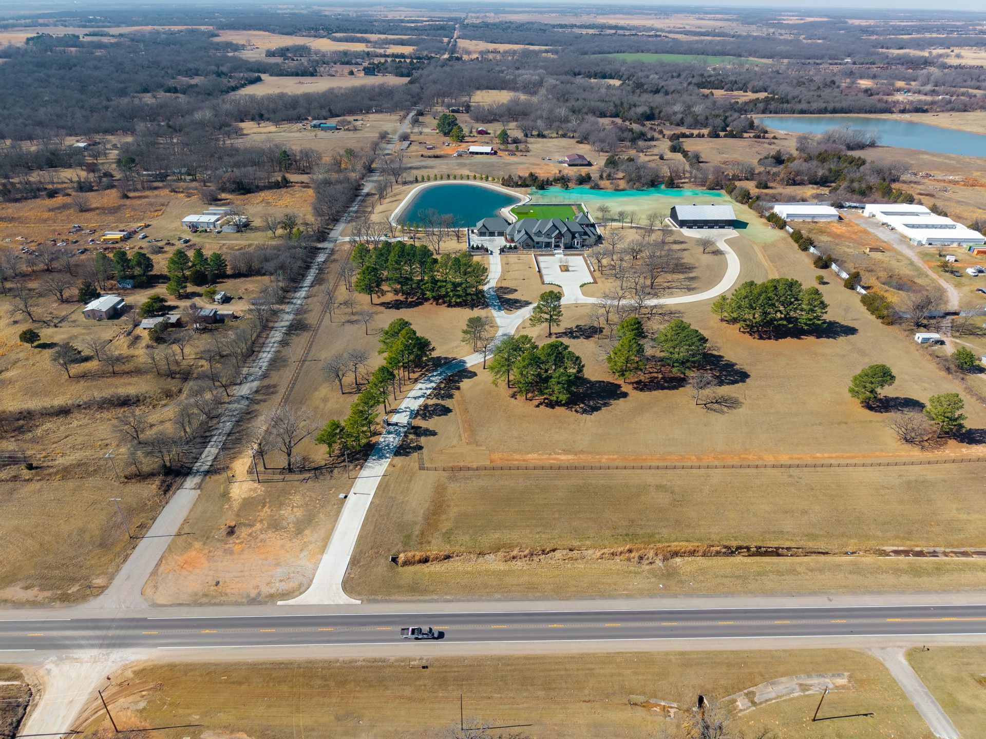 Red cattle chute and squeeze chute under a covered structure near a grassy field.