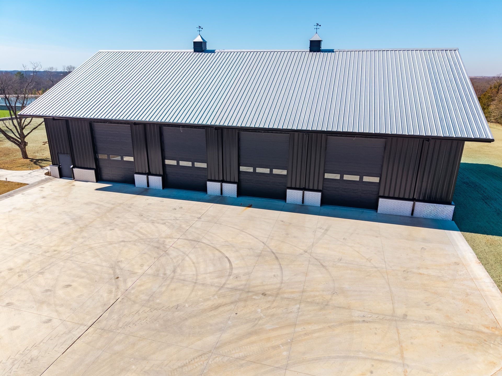 Red metal livestock handling equipment under a covered shelter, next to a grassy area.