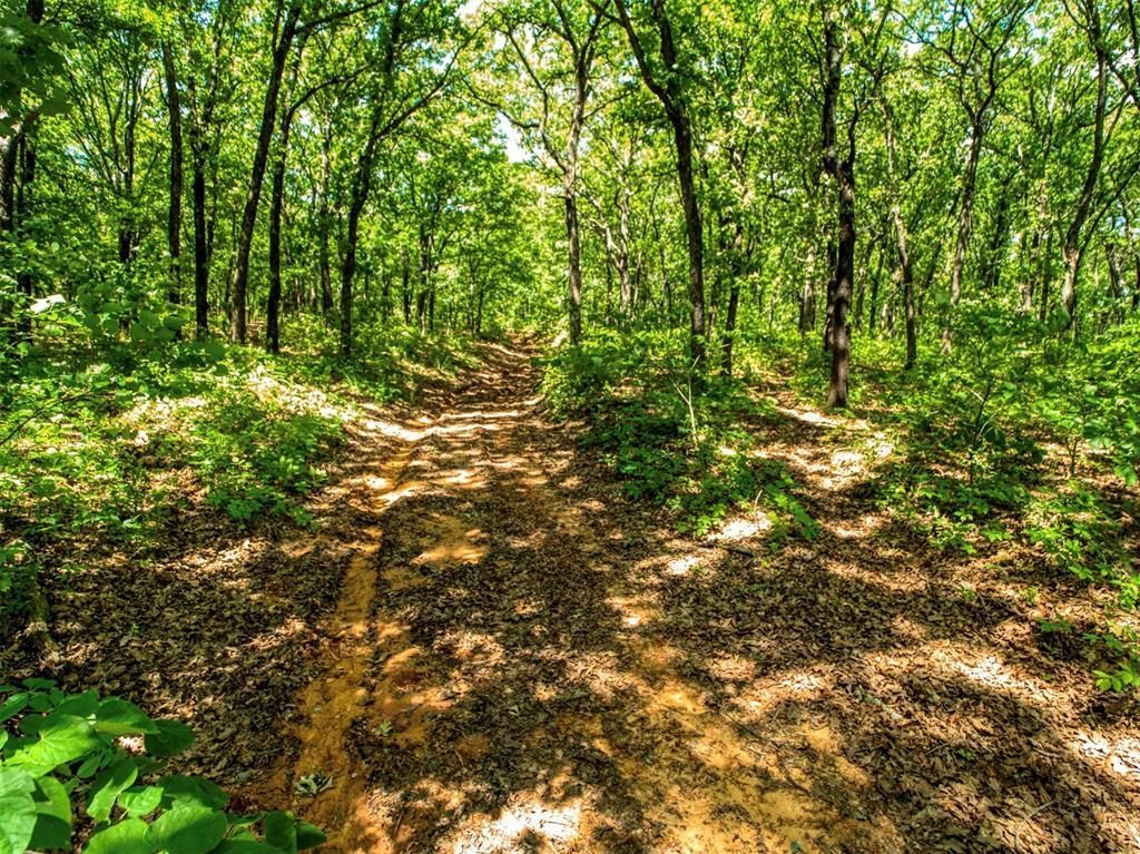 Aerial view of a rural property with buildings, a pond, and an outlined boundary in an open field.