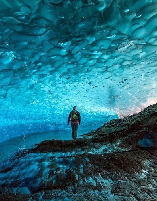 A man is walking through an ice cave in Juneau AK. Local Tour Guide Jeff Hoover