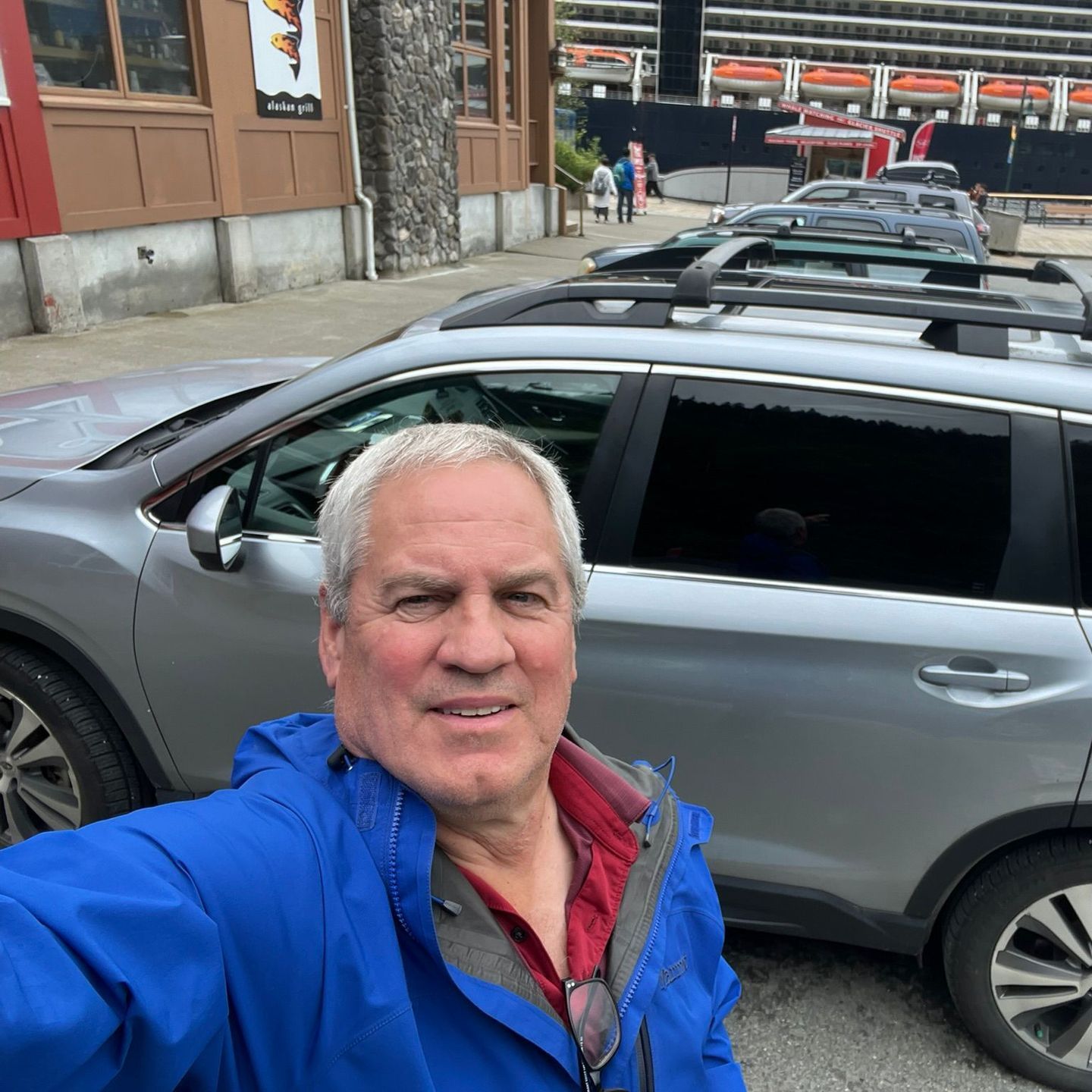 Jeff Hoover in a blue jacket is taking a selfie in front of a silver suv. Local Tour Guide in Juneau, AK. Unique Juneau Tours