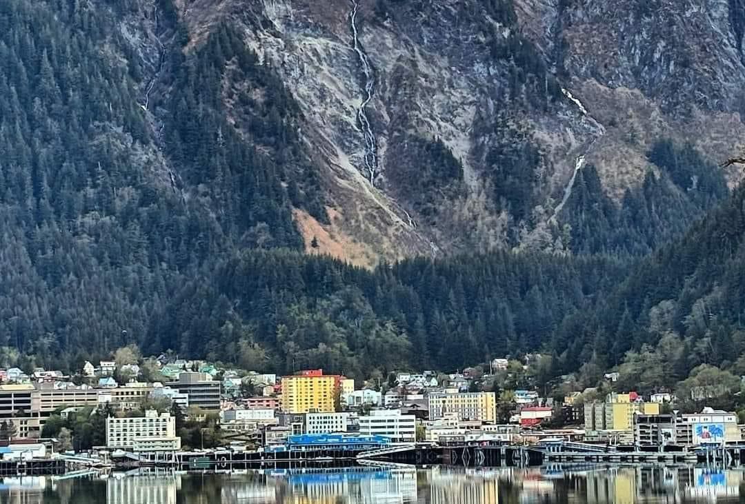A city is sitting on the shore of a lake with mountains in the background in Juneau AK. Local Tour Guide