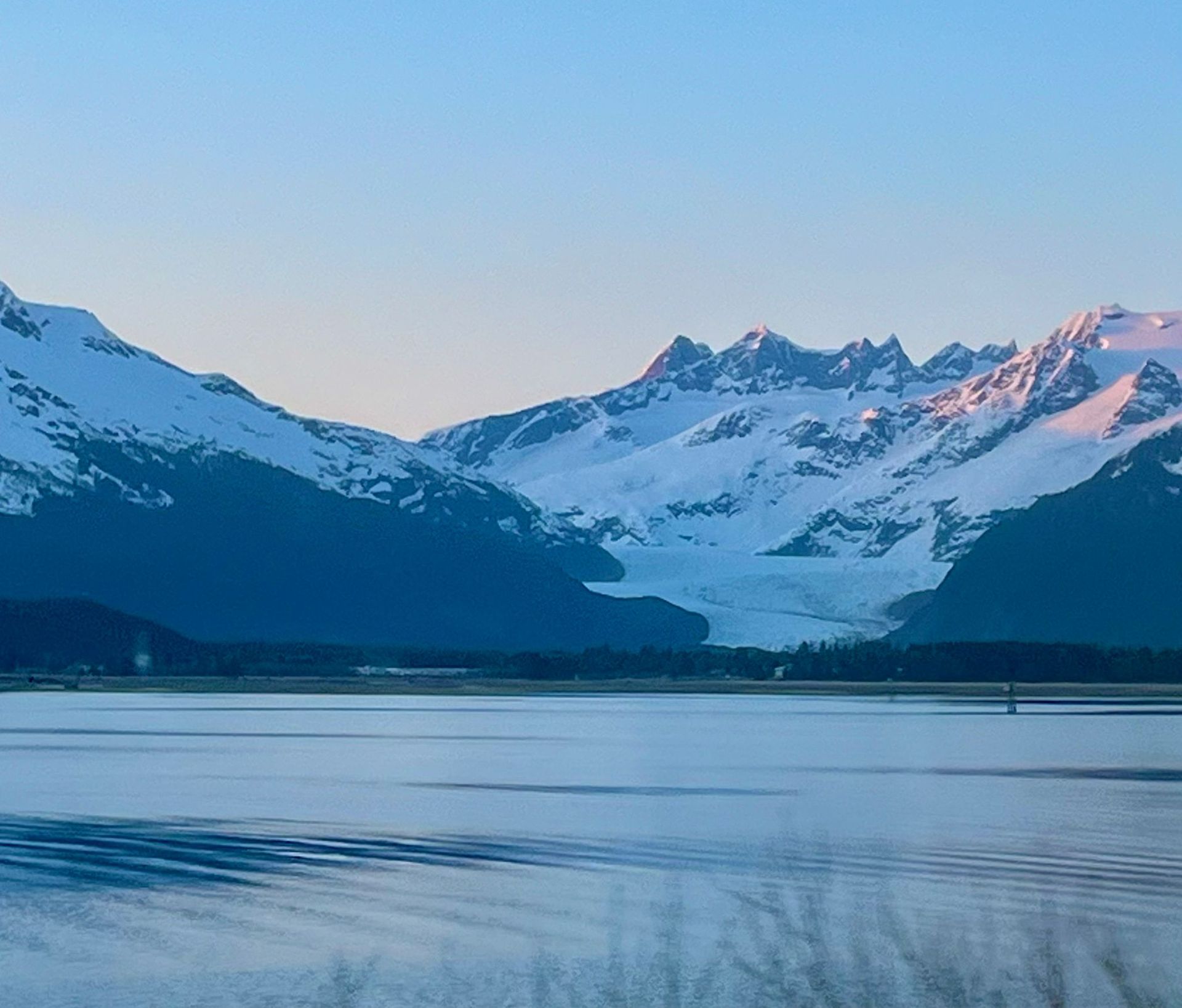 A lake with snowy mountains in the background in Juneau AK. Local Tour Guide in Juneau, AK. Unique Juneau Tours