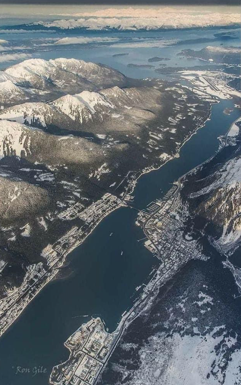 An aerial view of a river surrounded by snow covered mountains in Juneau AK. Local Tour Guide in Juneau. Unique Juneau Tours