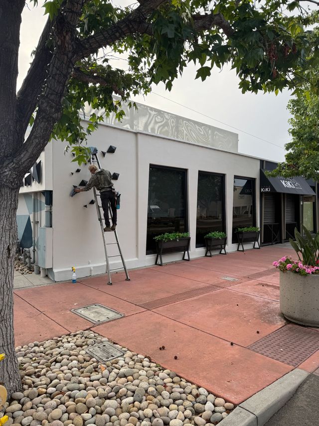Sliding glass window on a stucco exterior wall, reflecting trees and a patio with a bicycle.