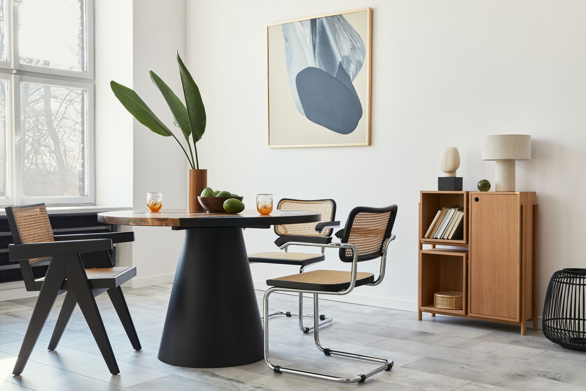 A dining room with a table and chairs and a painting on the wall.