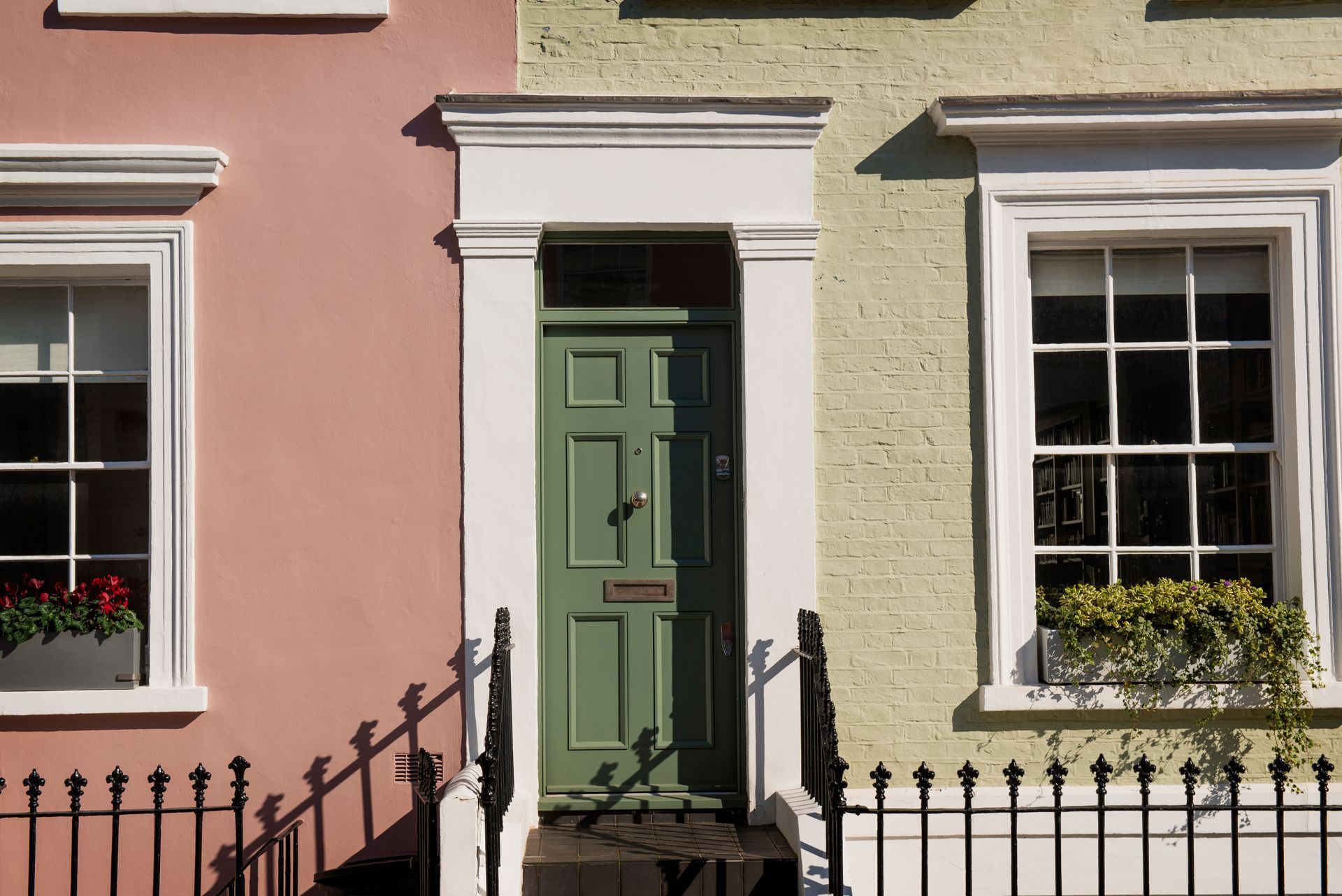 A green door is between two pink and yellow houses.