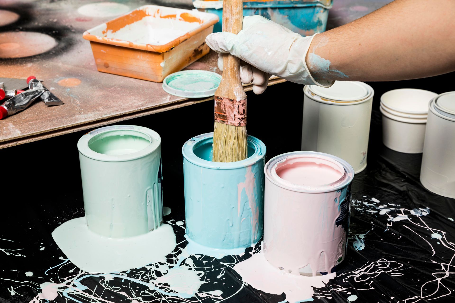 A person is holding a brush in a can of paint.